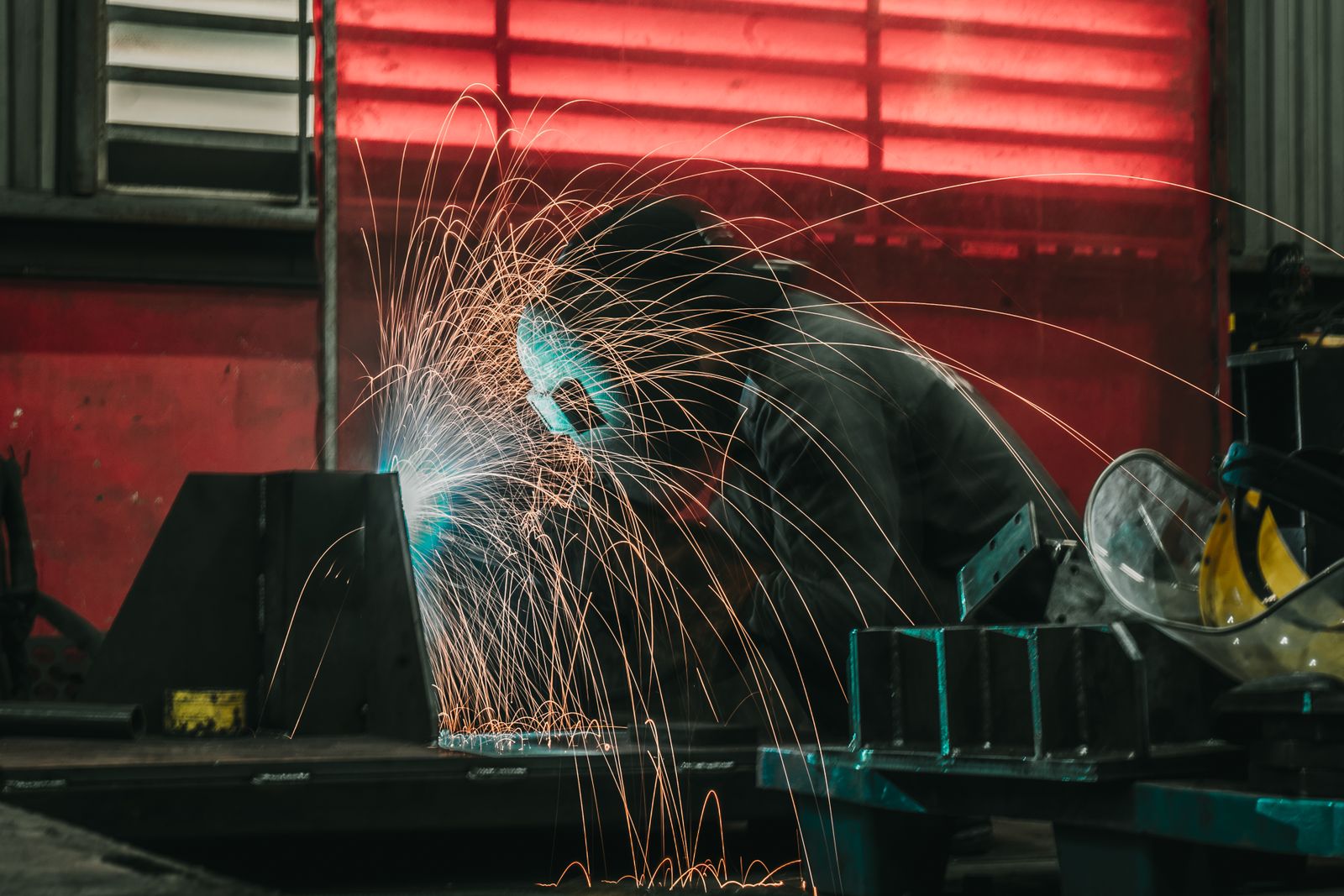 Soldador a soldar metal em oficina, com faíscas