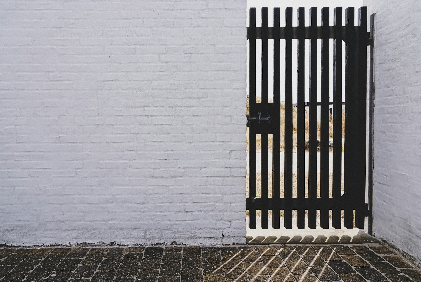 Portão pedonal metálico preto instalado em muro exterior